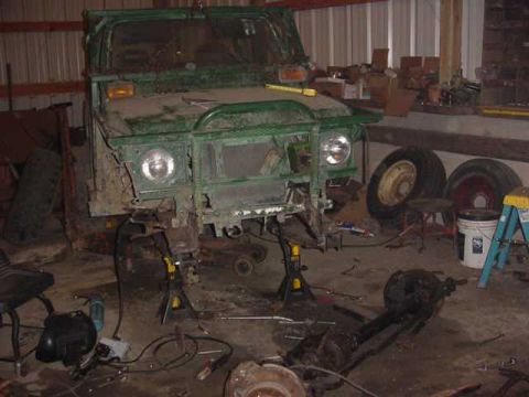 1992 Ford Bronco - Green off-road vehicle undergoing repairs in a workshop, with parts and tools scattered around.
