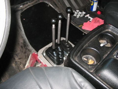 1991 Ford Bronco - The interior of a vehicle features a complex shifter setup with three levers, suggesting a manual transmission and possibly four-wheel driv…