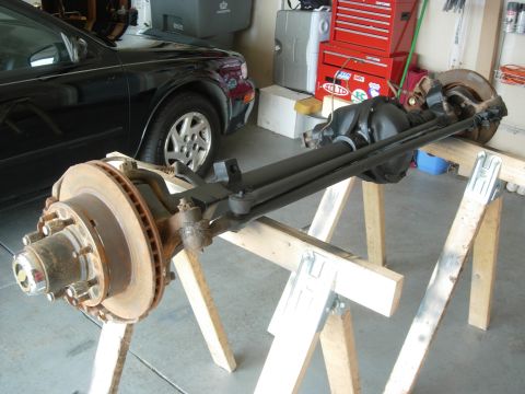 1995 Ford Bronco - Front axle assembly with disc brake rotor and tie rod assembly is shown supported by sawhorses.