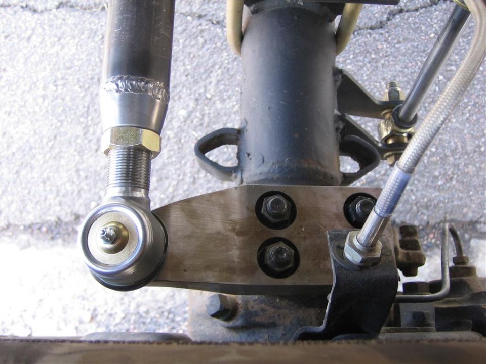 Custom steering link with heim joint and fabricated steel arm bolted to axle, braided brake line
