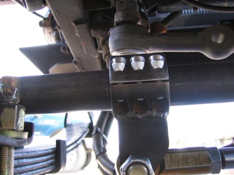 1987 Suzuki Samurai - Close-up view of a custom high steer arm modification on a vehicle's suspension system, with a SuperMotors logo visible.