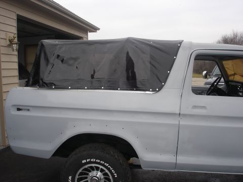 1979 Ford Bronco - This 1978 Ford Bronco is seen from the side, partially covered by a black soft top.