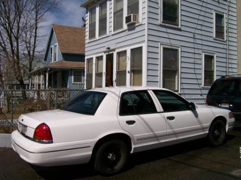 1999 Ford Crown Victoria - Side view of a white Ford Crown Victoria sedan parked on a street.