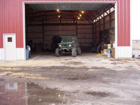 1992 Ford Bronco - A green off-road vehicle sits inside a large red barn with the doors open.