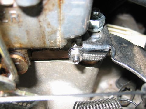 1985 Ford LTD Crown Victoria - A close-up view of a carburetor's linkage mechanism, showing a hose clamp securing a part and a visible spring.