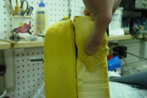 1993 Ford Bronco - A hand is shown tearing away yellow foam from a seat cushion, revealing the underlying structure.