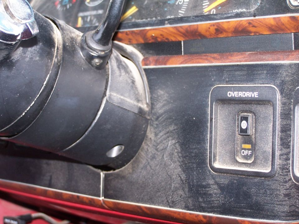 Truck interior showing steering column and an OVERDRIVE on/off switch on woodgrain dash