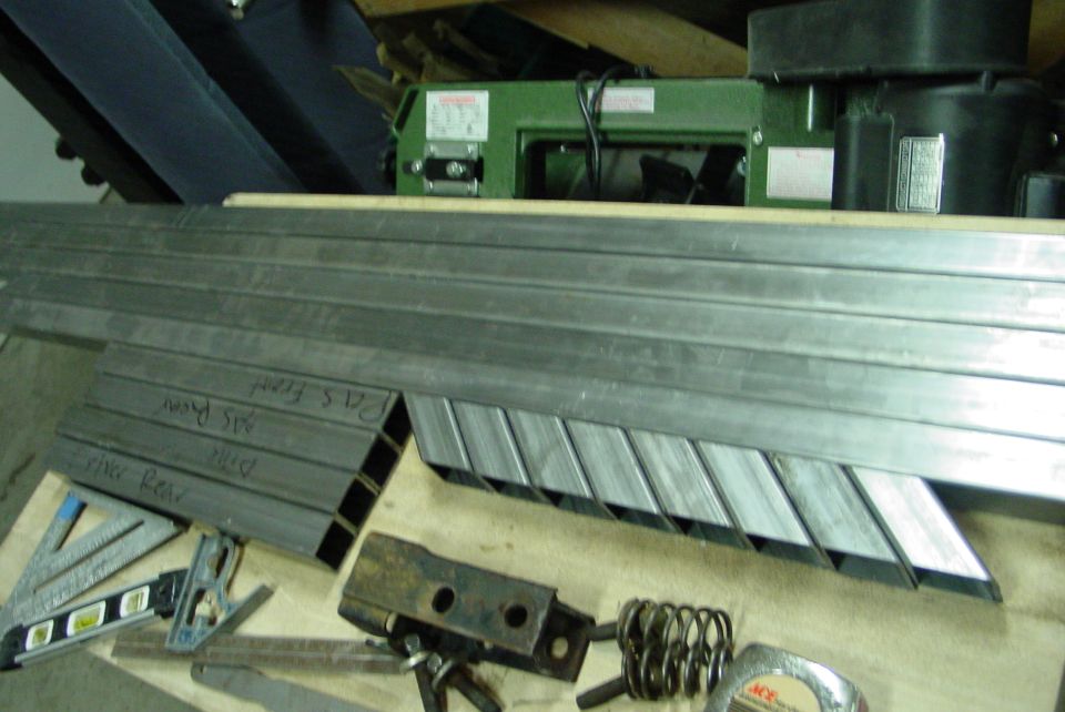 Metal tubing cut at angles, with handwritten labels 'Pat's Front', 'ABS Pipe', 'Rear'. Tools include a level and square