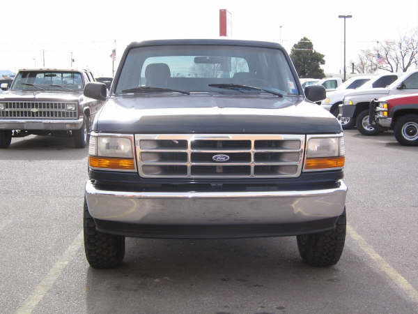 Front view of a dark blue 1995 Ford Bronco parked in a lot with other vehicles