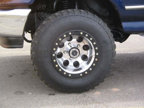 1995 Ford Bronco - A close-up view of a modified wheel and tire assembly on a blue SUV.