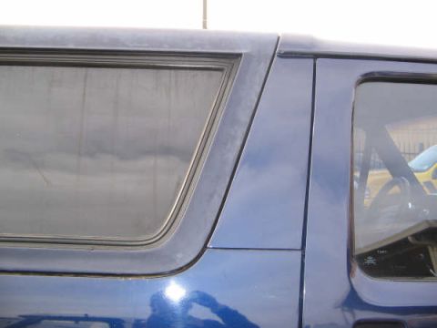 1995 Ford Bronco - Close-up of the side profile of a blue 1995 Ford Bronco, focusing on the window frames and body panels.