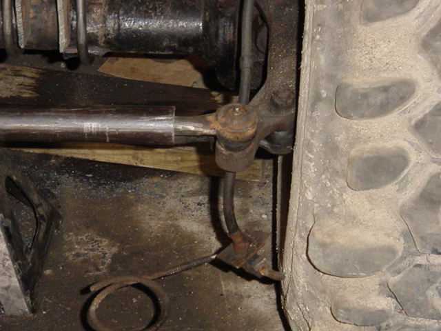 Close-up of a rusty tie rod end and steering linkage connected to a vehicle's wheel hub