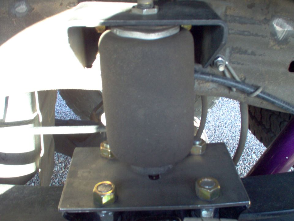 Close-up of an air suspension bag mounted to a vehicle frame with bolts