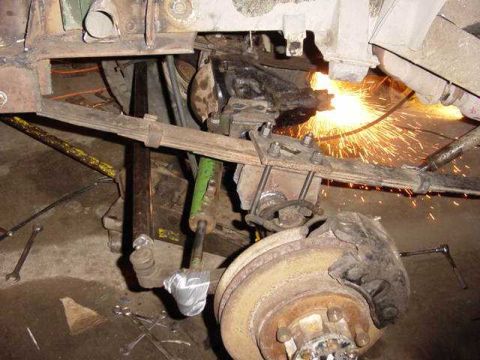 1992 Ford Bronco - Close-up of vehicle suspension work with sparks flying from a grinder.