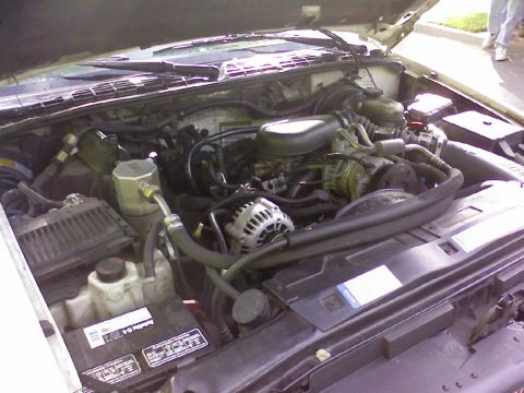 1995 Ford Bronco - The engine compartment of a vehicle is shown with the hood open, revealing the motor and its components.