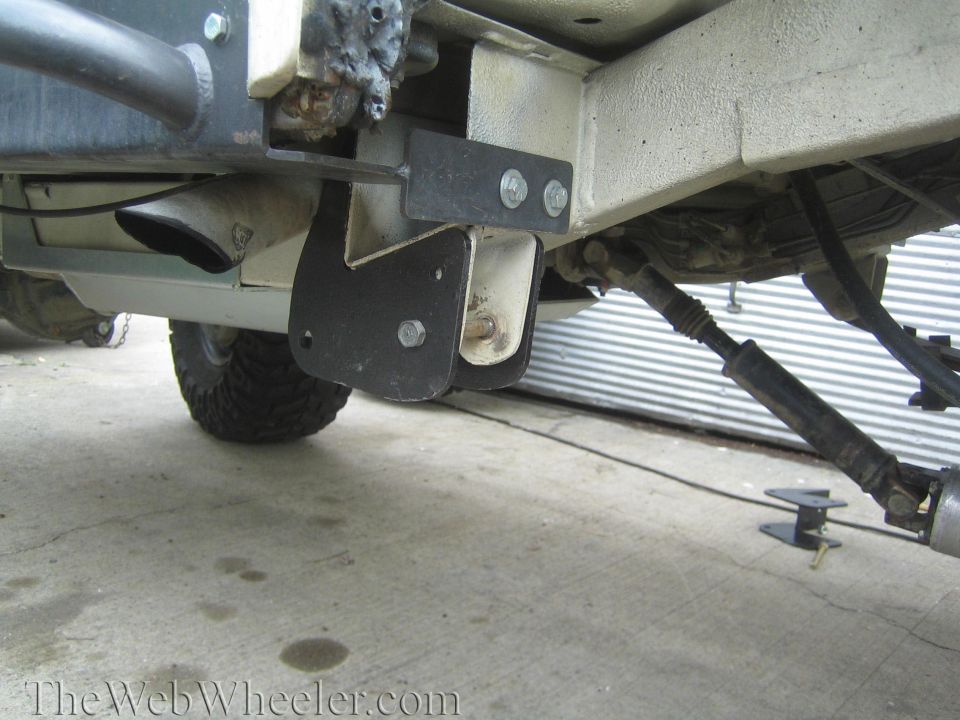 Black fabricated frame bracket bolted under a lifted 4x4 with exhaust tip and off-road tire