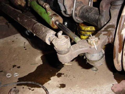 1992 Ford Bronco - Undercarriage view shows worn steering and suspension parts, with fluid leaks on the ground.