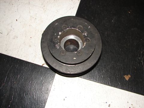 1992 Ford Taurus - A metal crankshaft pulley sits on a black and white checkered floor.