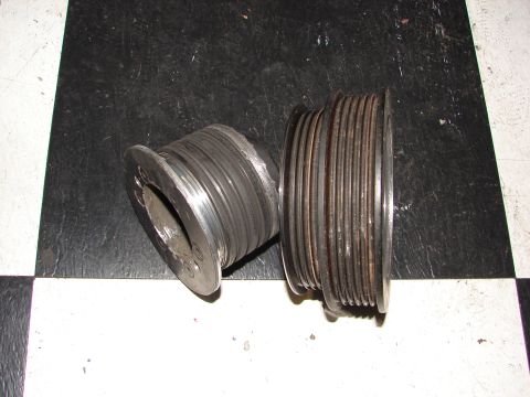 1992 Ford Taurus - Two metal pulleys with multiple grooves are shown on a checkered surface.
