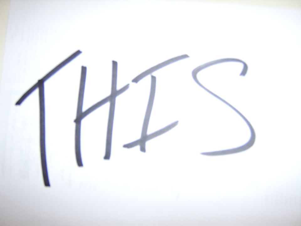 Handwritten word 'THIS' on white paper