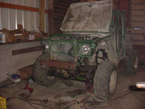 1992 Ford Bronco - An off-road vehicle is parked indoors with its hood up, revealing its engine and modified front end.