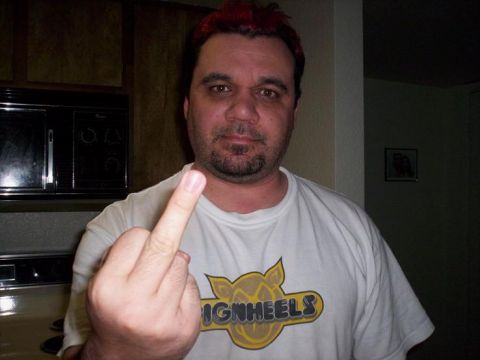 1989 Ford Bronco - Man with red hair and goatee gives the middle finger while wearing a t-shirt with a logo.