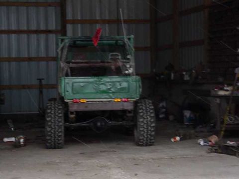 1992 Ford Bronco - This green pickup truck, viewed from the rear, is in a garage with large tires.