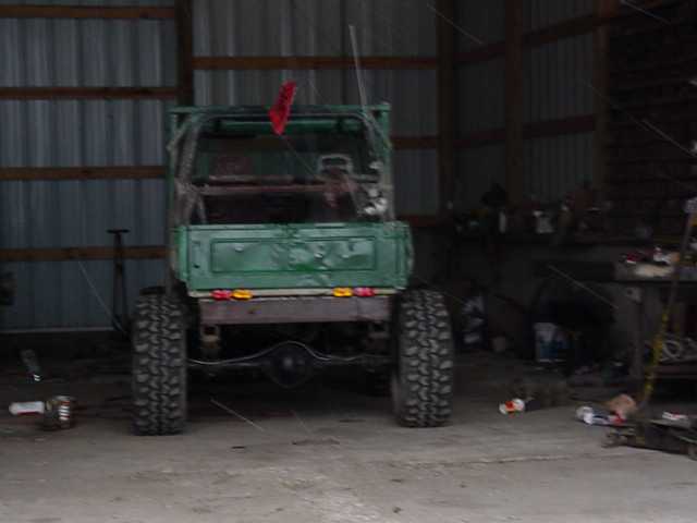 Green pickup truck with large tires, rear view, in a garage