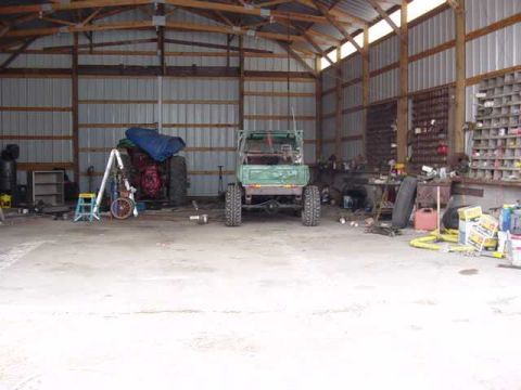 1992 Ford Bronco - A green off-road vehicle is parked inside a cluttered garage.