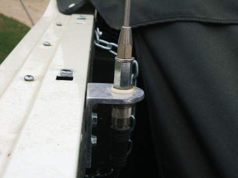 1991 Ford Bronco - Close-up of a homemade aluminum CB antenna mount bolted to the inner lip of a white truck bed rail, with a stainless whip screwed into the…