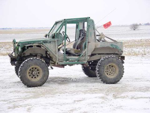 1992 Ford Bronco - Custom off-road vehicle with roll cage and large tires sits in a snowy landscape.