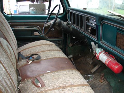 1996 Ford Bronco - Interior view of a green truck, a bench seat and a mounted fire extinguisher. Another vehicle is visible through the window.