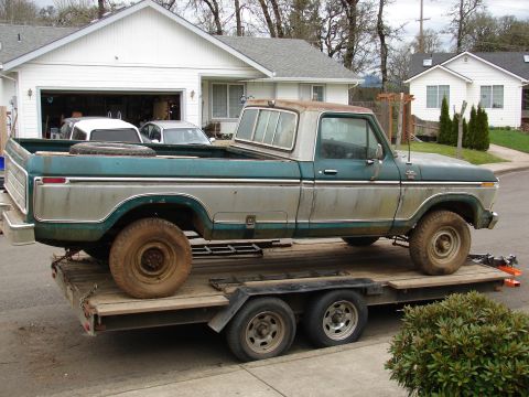 1996 Ford Bronco - This vintage Ford pickup is being transported on a trailer, with other vehicles visible in the driveway.
