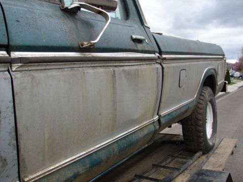 1996 Ford Bronco - Side view of a weathered Ford F-Series truck, likely from the mid-1970s, on a trailer.