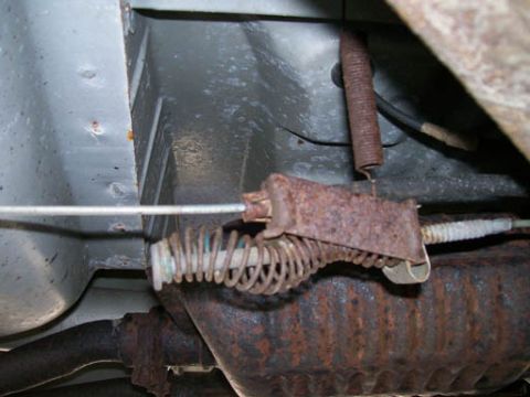 1999 Ford Crown Victoria - Underbody view of a rusty parking brake cable mechanism and spring.