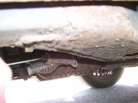1999 Ford Crown Victoria - The underbody of a vehicle displays significant rust and corrosion, with a visible tire and exhaust system.