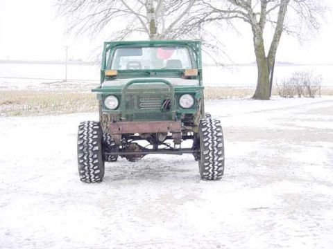 1992 Ford Bronco - A green off-road vehicle sits in a snowy landscape, its front end and large tires clearly visible.