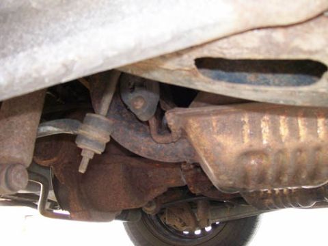 1999 Ford Crown Victoria - The underbody of a 1999 Ford Crown Victoria displays significant rust on its exhaust system and suspension components.