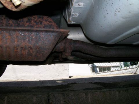 1999 Ford Crown Victoria - Close-up of the underbody exhaust system, showing significant rust on the muffler and pipes.