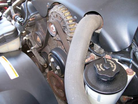 1999 Ford Crown Victoria - Close-up of engine components including belts and pulleys, with a power steering fluid reservoir.