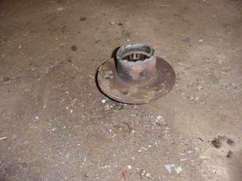 1992 Ford Bronco - A heavily rusted wheel hub sits on a dusty concrete surface, showing signs of wear and damage.