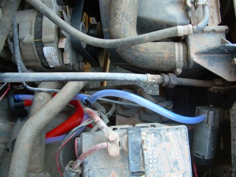 1992 Ford Bronco - Close-up view of the engine compartment, focusing on the battery and alternator with visible hoses and wiring.