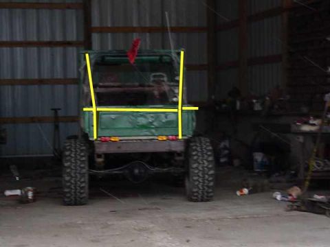 1992 Ford Bronco - Green off-road vehicle with yellow markings, viewed from the rear inside a workshop.