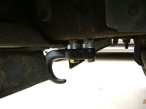 1991 Ford Bronco - Underside close-up of a black tow hook bolted to the front frame rail of a truck or SUV, secured with two zinc-plated bolts. Surrounding fr…