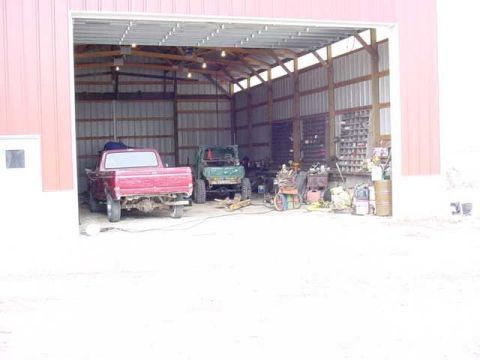 1992 Ford Bronco - A red 1992 Ford Bronco is parked inside a barn next to a green utility vehicle.