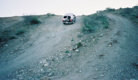 1996 Ford Bronco - SUV navigates a challenging off-road incline on a dusty trail.