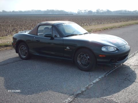 1995 Ford Probe - This dark green convertible sports car is seen from a three-quarter front view on a paved road with a field in the background.