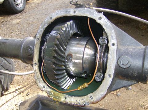 1986 Ford Bronco - Close-up of an open differential housing, revealing internal gears and a copper brake line.
