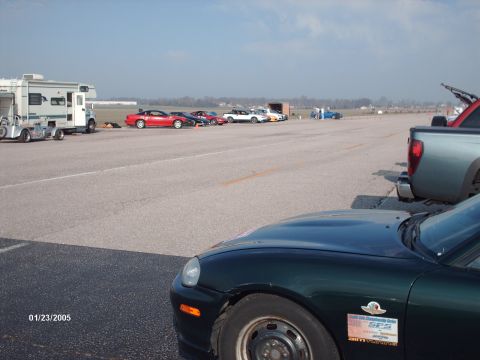 1995 Ford Probe - A dark green car's front corner is visible in the foreground, with other vehicles and an RV in the background on a sunny day.
