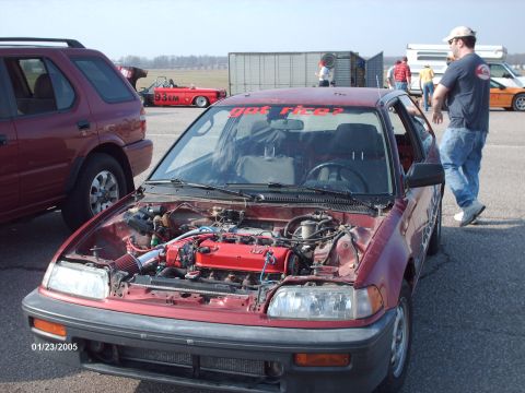 1995 Ford Probe - Red hatchback with engine exposed and a "got rice?" sticker on the windshield.